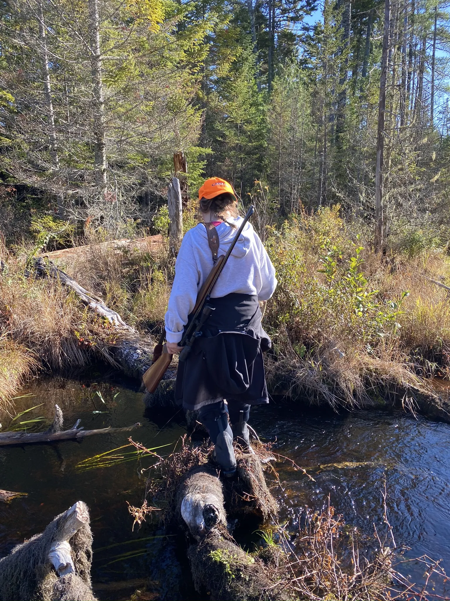 Hunter crossing water on log