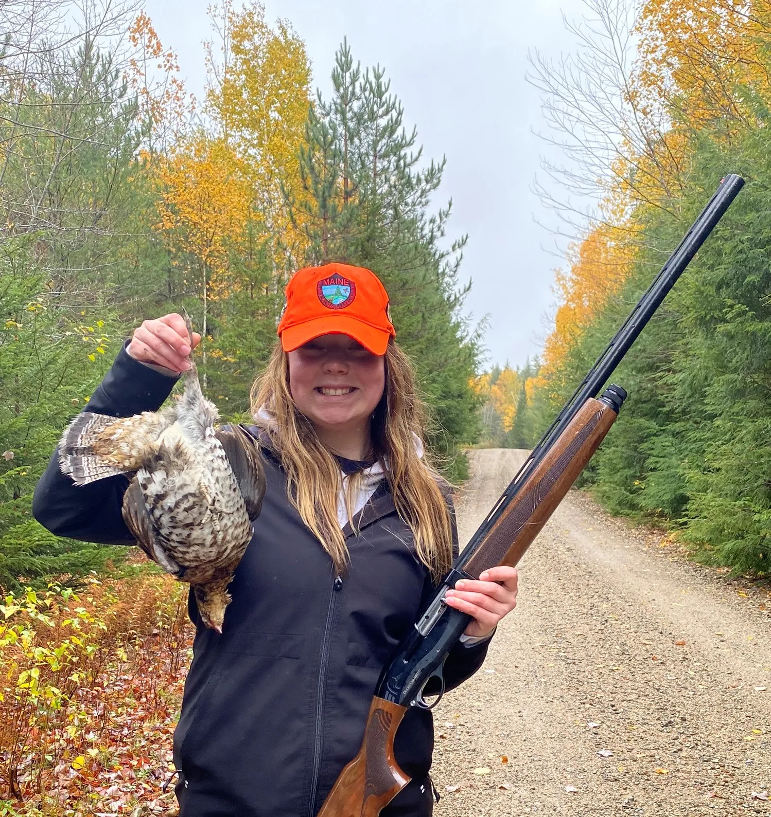 female hunter and grouse on Maine woods road